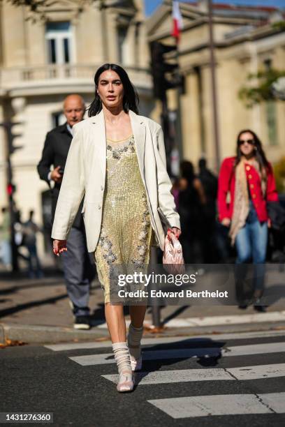 Brittany Xavier wears a white latte oversized blazer jacket, a yellow rhinestones with gray embroidered sequined pattern knees skirt from Miu Miu, a...