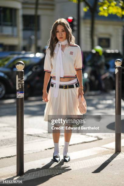 Jenny Suet In Tsang wears a white striped print pattern / short sleeves / blue and red striped borders print pattern polo shirt from Miu Miu, a dark...