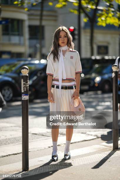 Jenny Suet In Tsang wears a white striped print pattern / short sleeves / blue and red striped borders print pattern polo shirt from Miu Miu, a dark...