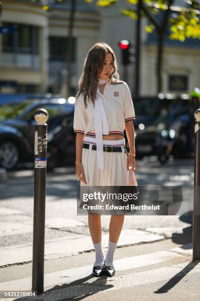 Jenny Suet In Tsang wears a white striped print pattern / short sleeves / blue and red striped borders print pattern polo shirt from Miu Miu, a dark...