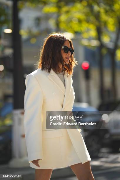 Christine Centenera wears black sunglasses from Louis Vuitton, a pale gray t-shirt, a white buttoned blazer jacket dress, outside Miu Miu, during...