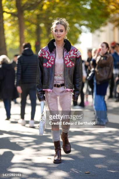 Emili Sindlev wears gold earrings, a diamonds necklace, a pale pink tulle with embroidered flower pattern knees dress from Miu Miu, a dark brown...