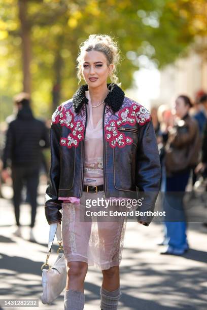 Emili Sindlev wears gold earrings, a diamonds necklace, a pale pink tulle with embroidered flower pattern knees dress from Miu Miu, a dark brown...