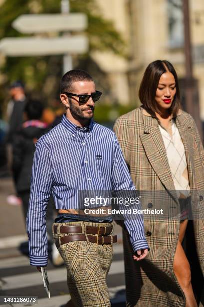 Pelayo Diaz wears black sunglasses from Ray Ban, a navy blue and white striped print pattern cropped shirt from Miu Miu, beige and brown with black...