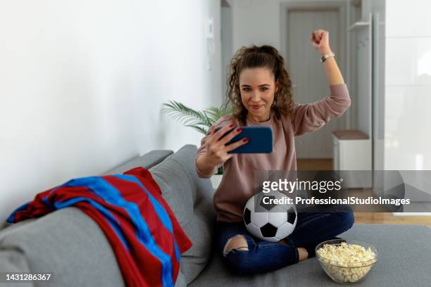 beautiful sports fan watching the game alone on phone - pre game stockfoto's en -beelden