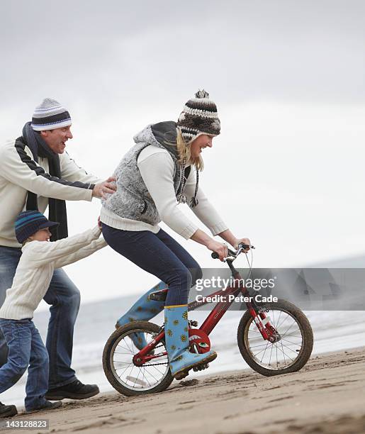 family with bike on beach in winter - pushing bike stock pictures, royalty-free photos & images