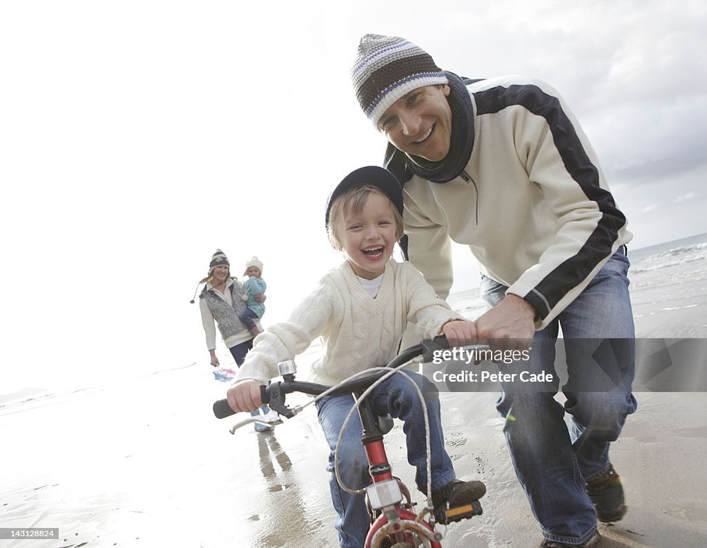 Family riding bike on beach in winter