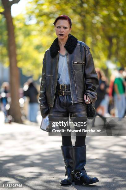 Courtney Trop wears a pale gray and gray jacquard print pattern wool pullover, a black faded shiny leather / black sheep collar jacket, a black...