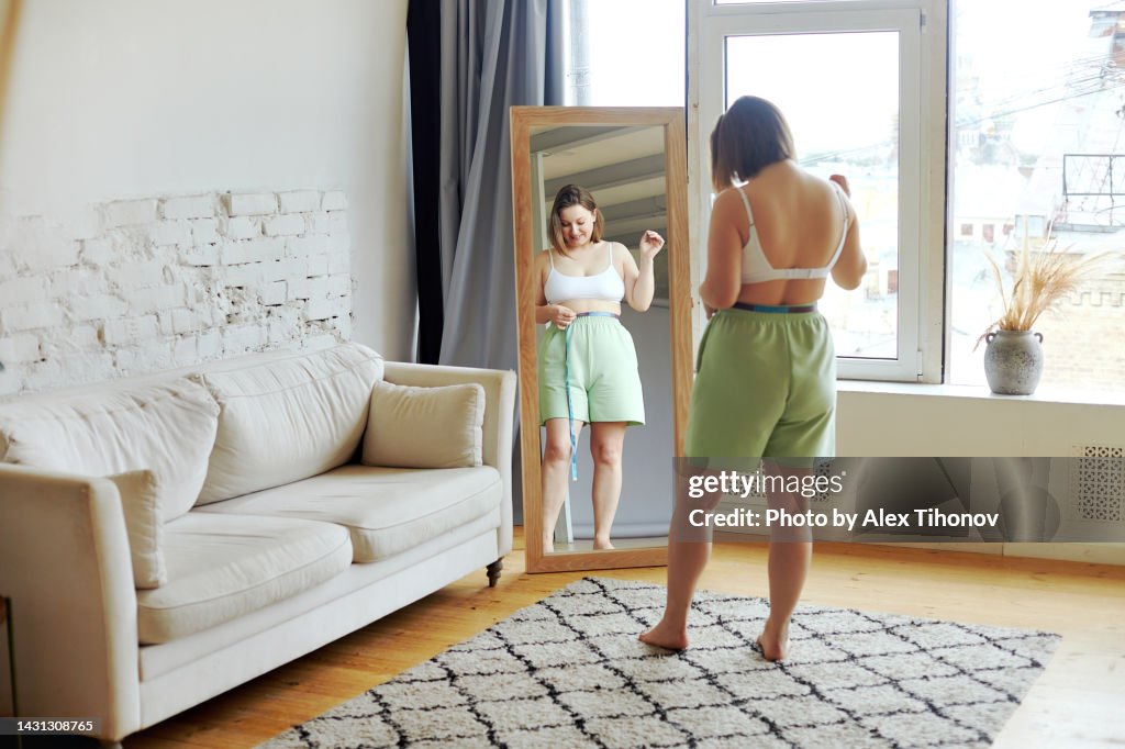 Plus size female holds measures tape check her waist size