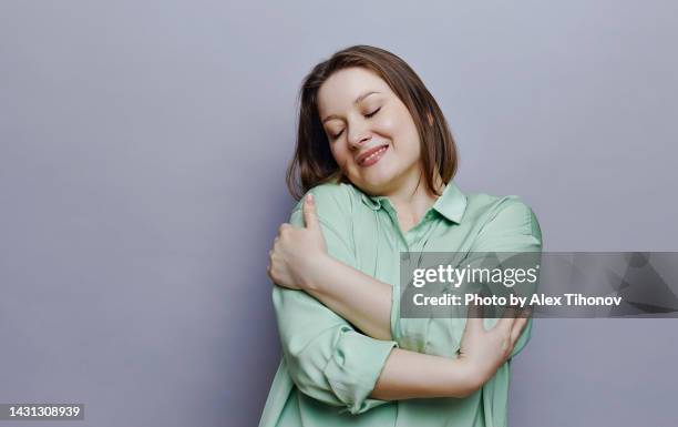 attractive oversize woman hugging oneself, posing on gray studio background - fat redhead stock pictures, royalty-free photos & images