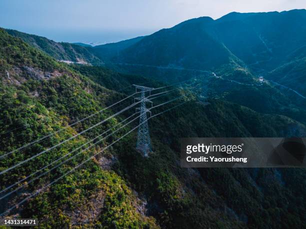 high voltage transmission lines are erected on the top of the mountain - alto voltaje fotografías e imágenes de stock