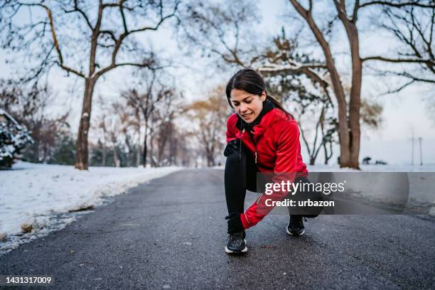 young woman twisting her ankle while jogging - fibula stockfoto's en -beelden