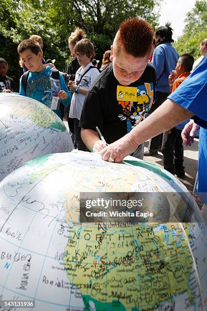 Anderson Elementary third-grader Miguel Perez signs his name on an inflatable globe during the "Boeing Wichita Presents: Earth Day Kansas" at the...