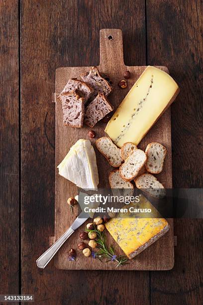 cheese, bread, and nuts served on cutting board - cheeses stock-fotos und bilder