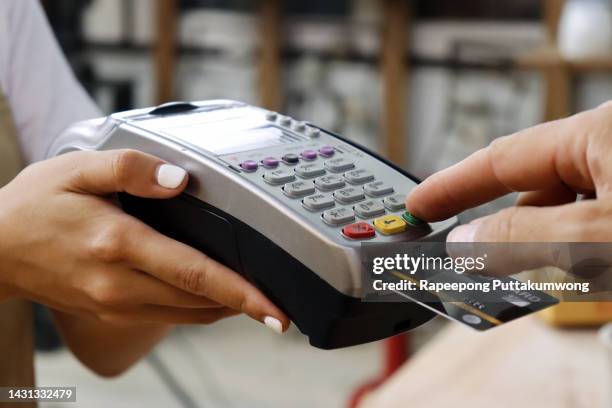 closeup of hand using credit card swiping machine to pay. male hand with credit card paying through terminal for payment in coffee shop. man entering debit card code in swipe machine. - marcar el número de identificación personal fotografías e imágenes de stock