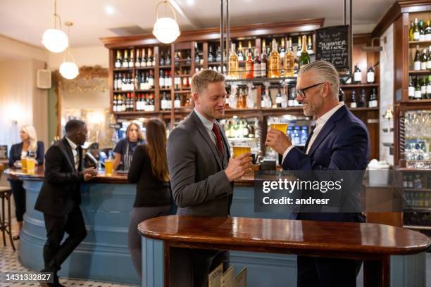 glückliche männer, die nach der arbeit in der kneipe etwas trinken - business talk englischer satz stock-fotos und bilder