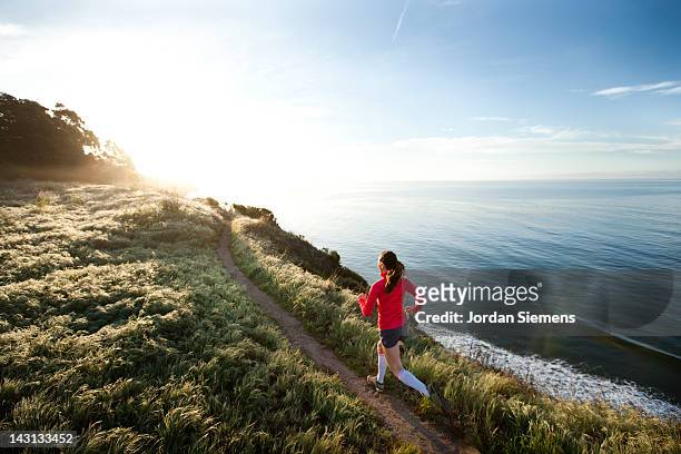 woman trail running near the ocean. - correre foto e immagini stock