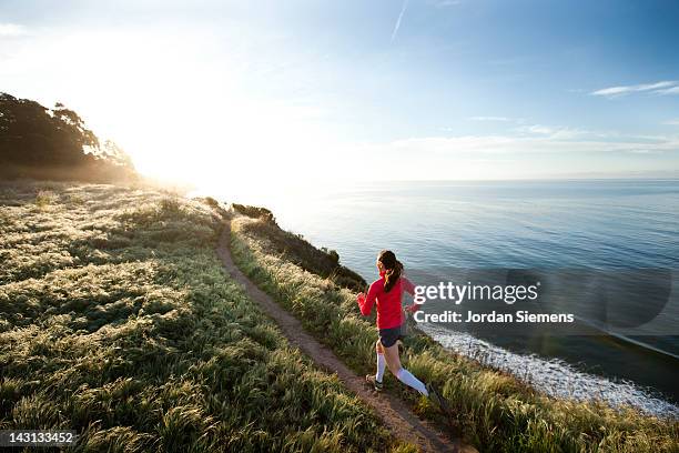 woman trail running near the ocean. - correr imagens e fotografias de stock