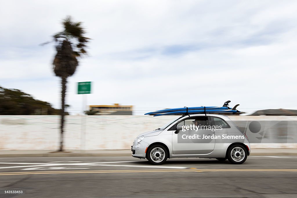A small car with surfboards.