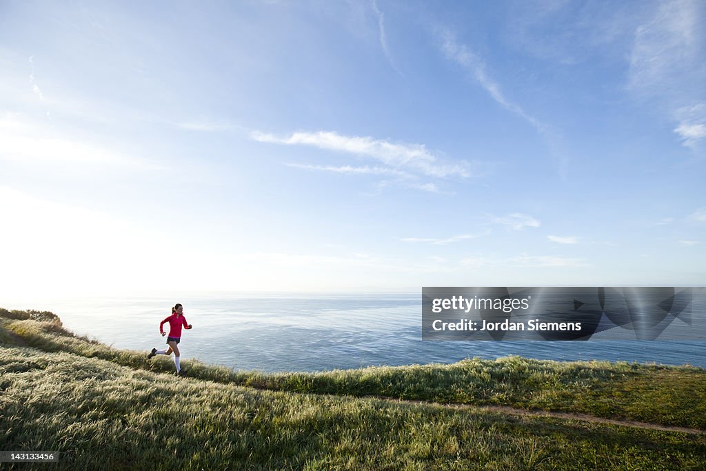 Woman trail running near the ocean.