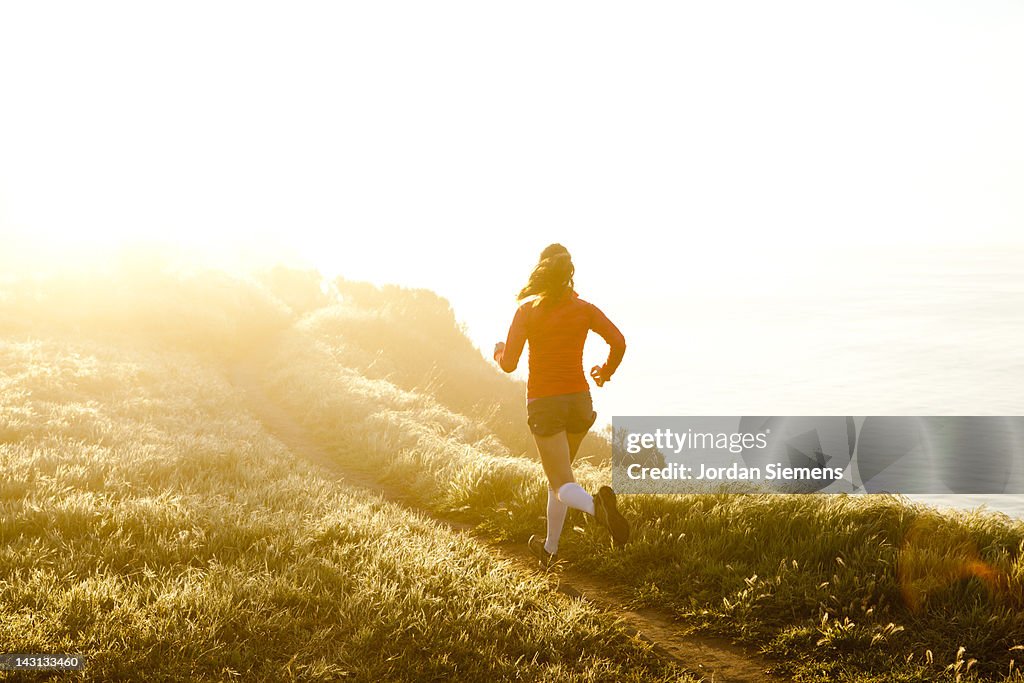Woman trail running near the ocean.