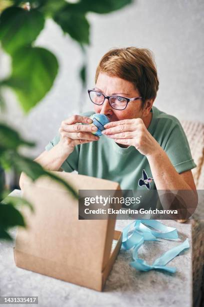 elderly woman cheerfully examines the contents of an eco gift, sniffs cosmetic products. - cosmetics box stock pictures, royalty-free photos & images