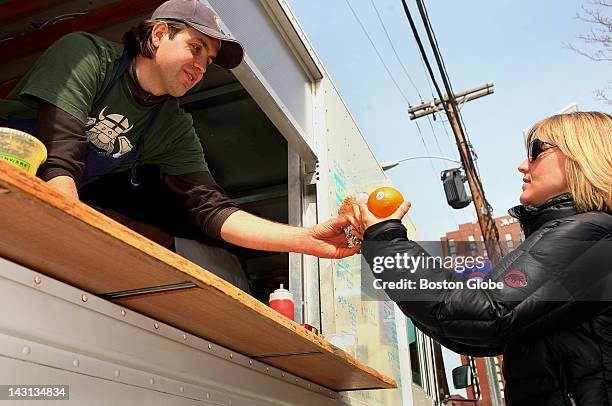 Clover Food Lab owner Ayr Muir, left, hands over an egg and eggplant sandwich to Lauren Mayhew at his food truck in Cambridge, Thursday, March 26,...