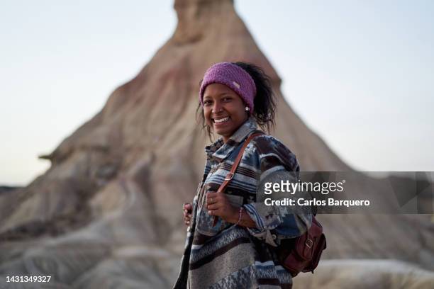 cheerful portrait of young nomadic latin woman looking at camera while standing at desert. - pioneer stock pictures, royalty-free photos & images