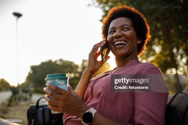 businesswoman relaxing on the bench on the city street, enjoying a coffee break from work - golden hour woman stock pictures, royalty-free photos & images