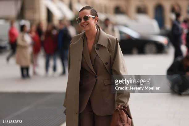 Guest is seen wearing beige transparent sunglasses, beige long coat, matching beige suit and a brown leather Loewe handbag, outside Chloe during...