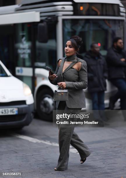 Guest is seen wearing a grey suit blazer with cut-outs and a matching suit pants, grey Hermès Kelly mini bag and black heels, outside Gauchere,...