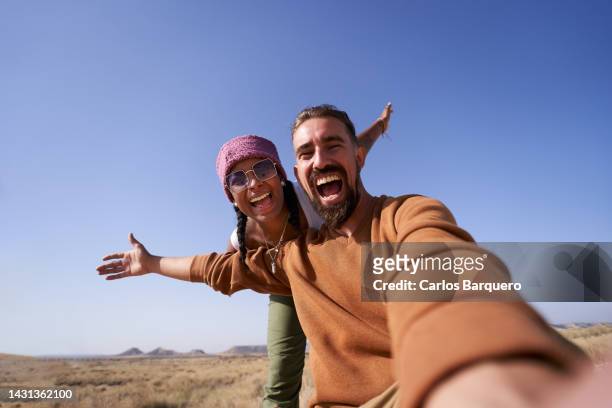 enthusiastic photo of nomadic couple taking a selfie showing the desert to post it on social media apps. - travel fotografías e imágenes de stock