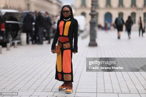 Guest is seen wearing black Chloé sunglasses, silver necklace, black with orange/brown/yellow pattern long dress, brown leather handbag and brown...