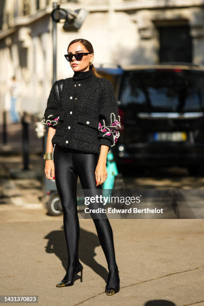 Evangelie Smyrniotaki wears black sunglasses, gold earrings, a black turtleneck pullover, a black checkered tweed with neon pink and white pearls...