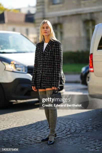 Linda Tol wears a white t-shirt, a silver and diamonds large necklace, a black with white checkered print pattern tweed jacket from Chanel, matching...