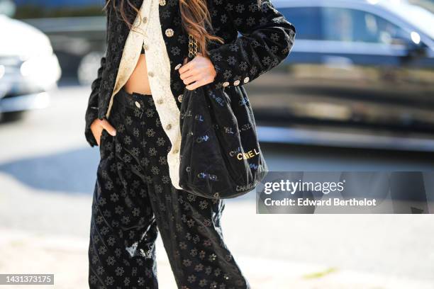 Chloe Harrouche wears a black with gold heart pendant earrings from Chanel, a white lace flower print pattern buttoned shirt from Chanel, a black...