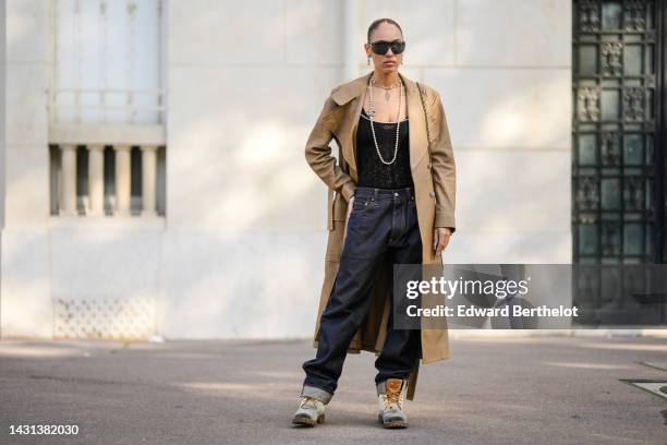 Hera Pradel wears black square futurist sunglasses from Chanel, a diamonds and pearls pendant logo earrings from Chanel, a white pearls and logo long...