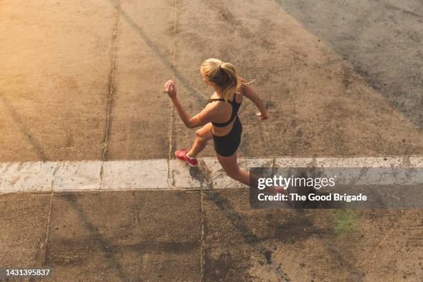 high angle view of woman running on street - carrera de carretera fotografías e imágenes de stock