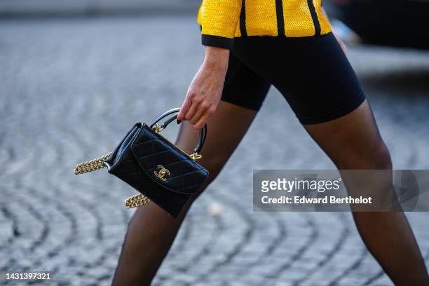 Sabina Jakubowicz wears a yellow sequined with black borders jacket, black cyclist shorts, black tights, a black shiny leather small Coco Handle...