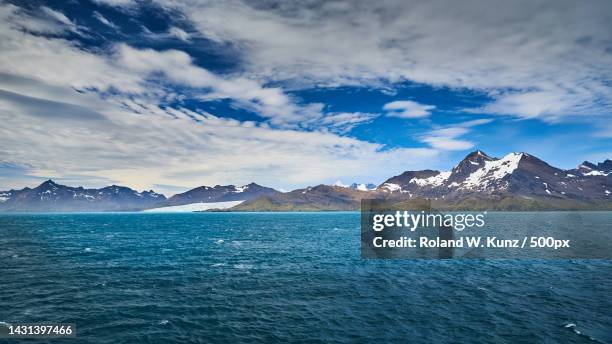 scenic view of sea by snowcapped mountains against sky,south georgia and the south sandwich islands - south georgia island fotografías e imágenes de stock