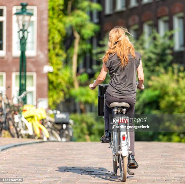 radfahrer in amsterdam - rückansicht - vintage rainwear stock-fotos und bilder