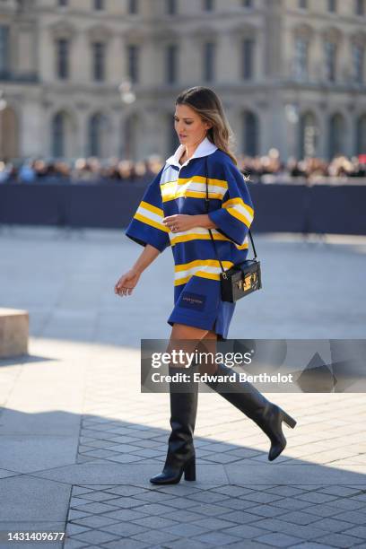 Guest wears a navy blue and yellow large straps and white print pattern oversized short sleeves / short dress from Louis Vuitton, a black Epi shiny...