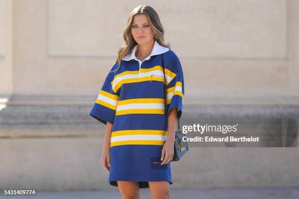 Guest wears a navy blue and yellow large straps and white print pattern oversized short sleeves / short dress from Louis Vuitton, a black Epi shiny...