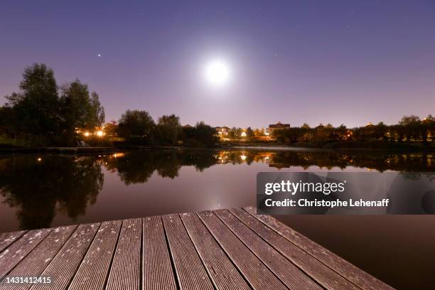 the moon above the pond of bussy saint georges, france - marne la vallée photos et images de collection