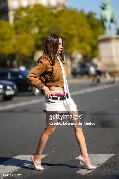 Guest wears black sunglasses, gold earrings, a brown suede with sheep collar bomber coat from Miu Miu, a white tulle turtleneck t-shirt, a white...