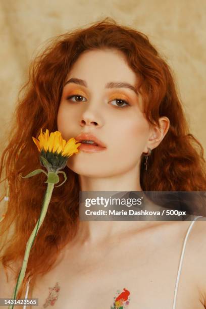 beautiful young woman with orange hair and yellow flower - editorial fotografías e imágenes de stock