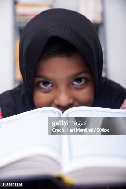 cute muslim little girl reading from traditional book,jakarta,indonesia - heri mardinal stock pictures, royalty-free photos & images