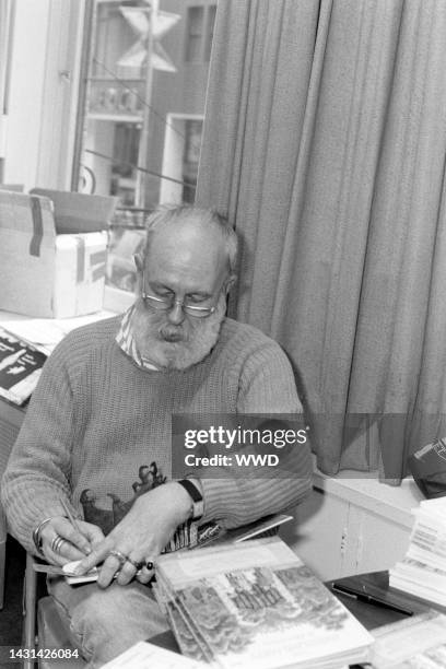 Writer Edward Gorey answers questions during an interview while signing his books.