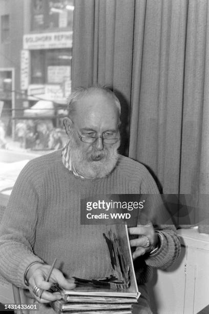 Writer Edward Gorey answers questions during an interview while signing his books.