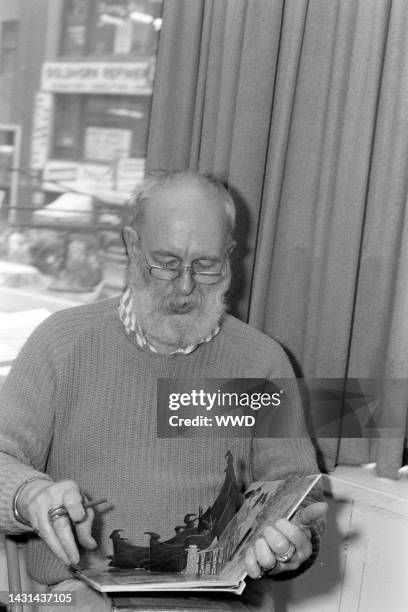 Writer Edward Gorey answers questions during an interview while signing his books.